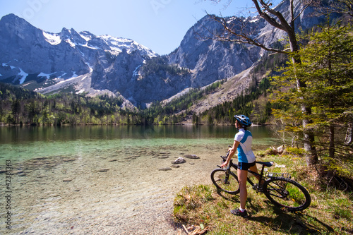 Yaung woman riding a bike beside Alpine lake