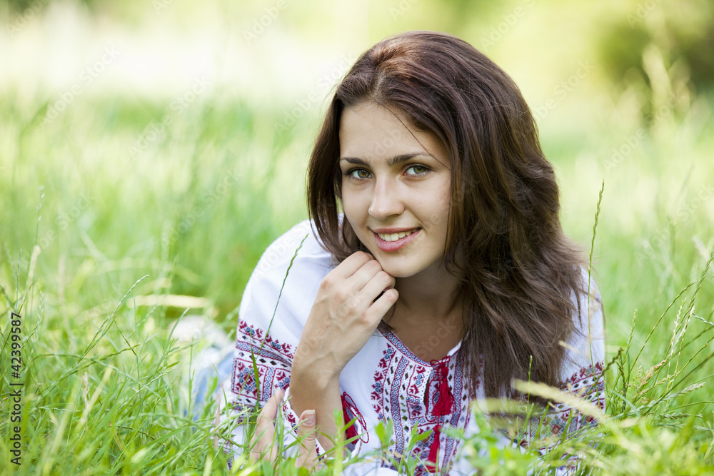 Slav teen girl at green meadow in national ukrainian clothing.