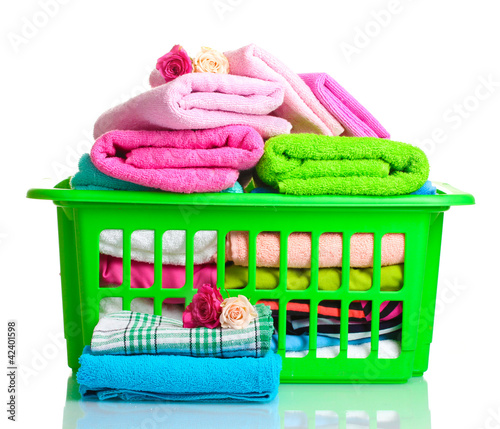 Towels in green plastic basket isolated on white photo