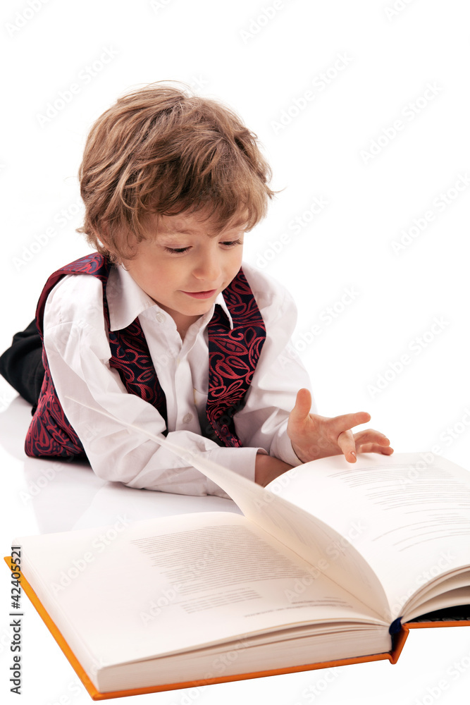 Preschooler reading a book while lying on the floor Preschooler reading a book while lying on the floor