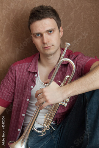 Handsome man hloding on a silver trumpet photo