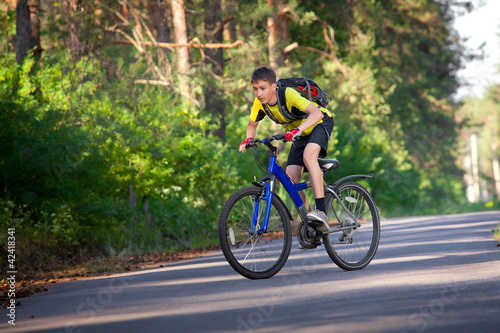 A teenager on a bicycle traveling in the forest