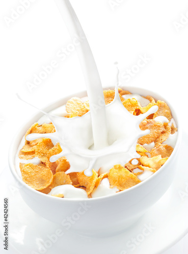 Milk pouring into a bowl of corn flakes photo