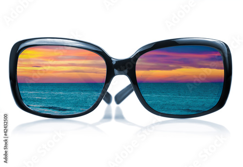Sunglasses reflecting a sunset at the sea
