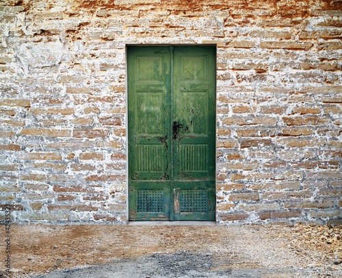 green wooden door on brick wall