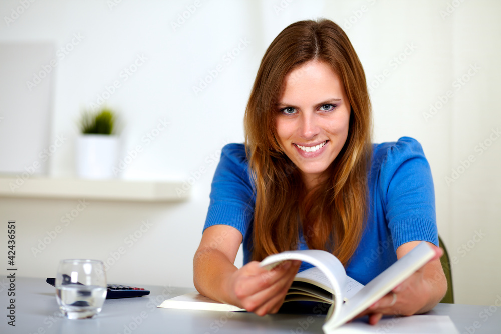 Lovely young woman smiling and reading a book Lovely young woman smiling and reading a book