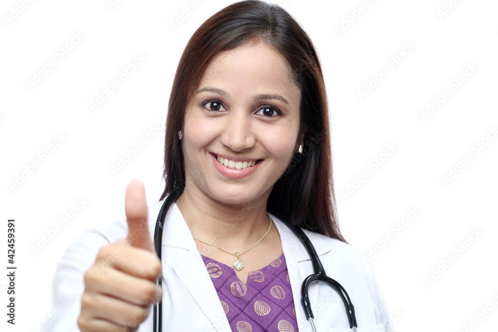 Female doctor with thumbs up gesture against white background