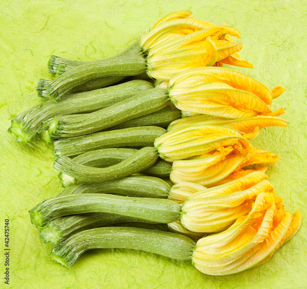 Courgettes or zucchini on green backgroung with flowers