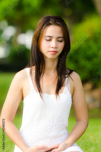 Beautiful healthy Young Woman meditating on the green grass