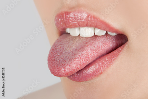 Fototapeta Young cheerful girl showing tongue