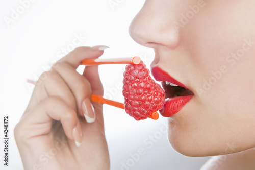 sexy girl holds chopsticks a raspberry near lips