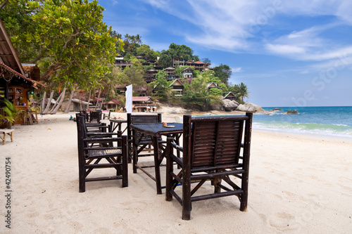 Chairs and table on the sand beach with blue sky