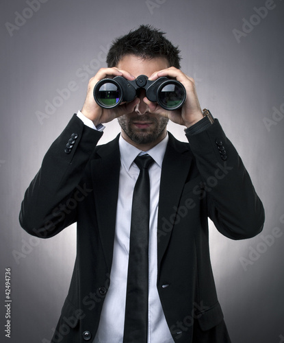Businessman looking through binoculars