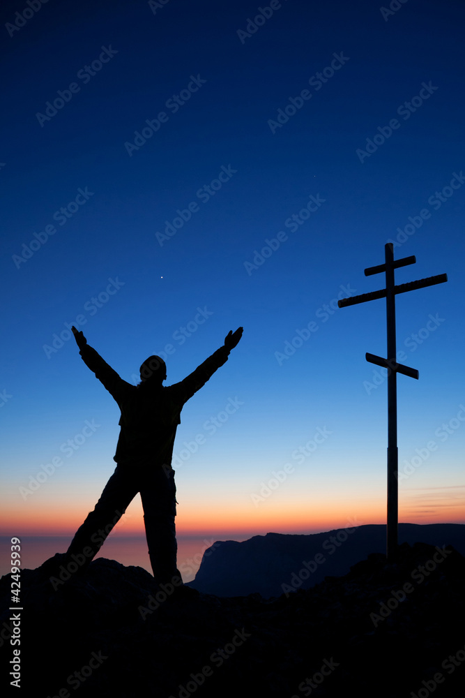 Man near the cross against the sky at sunset Man near the cross against the sky at sunset