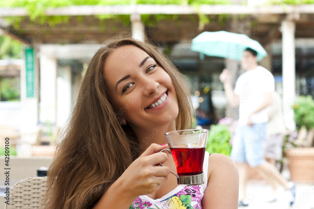 Young woman drinking tea in a cafe outdoors Young woman drinking tea in a cafe outdoors