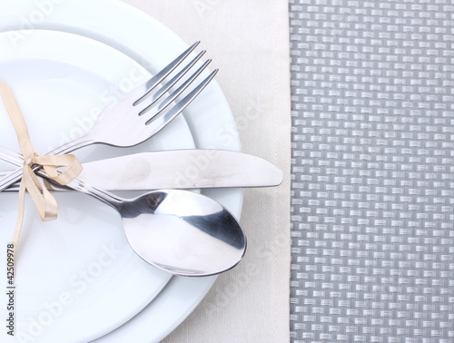 White empty plates with fork  spoon and knife tied with a ribbon