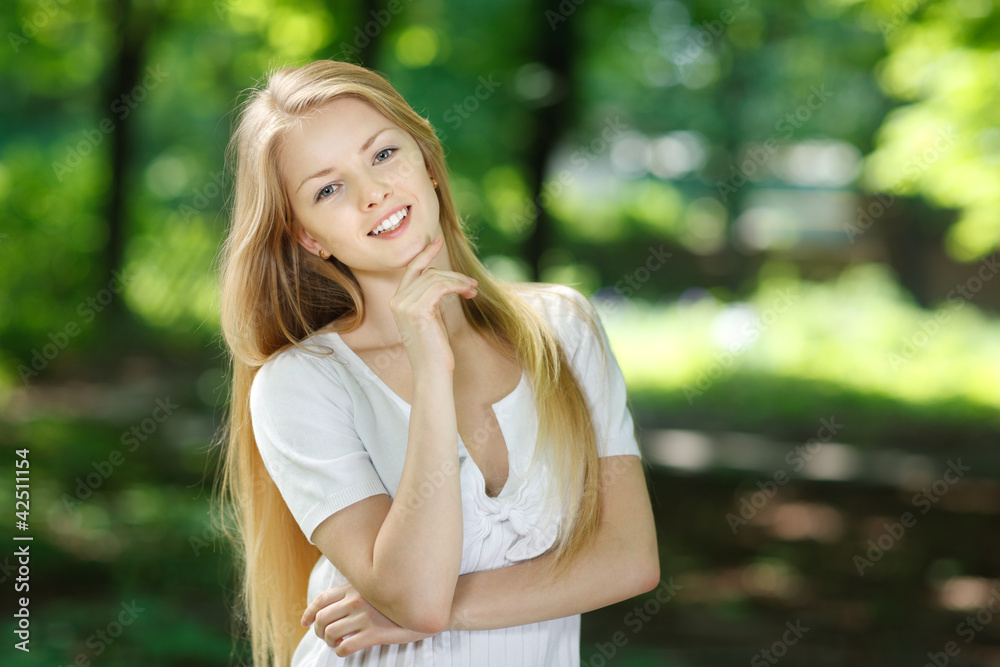 Smiling girl standing with folded hands over summer background Smiling girl standing with folded hands over summer background