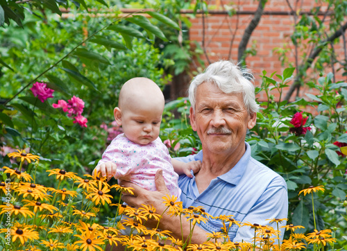 Grandfather with little grandson in a flowering garden