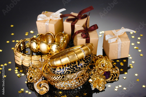 Beautiful golden jewelry and gifts on grey background photo