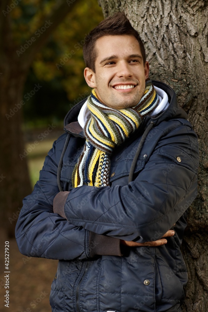 Happy young man standing by tree in park Happy young man standing by tree in park