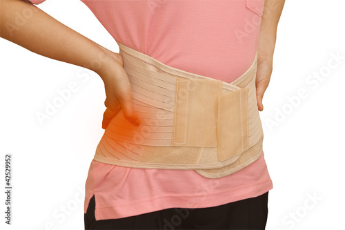 Woman in pain from back injury wearing lumbar brace corset photo