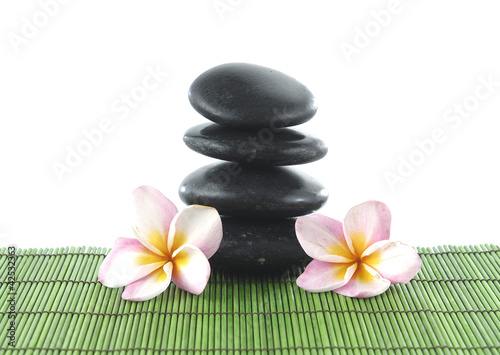 Two frangipani flower and stacked stones on green mat