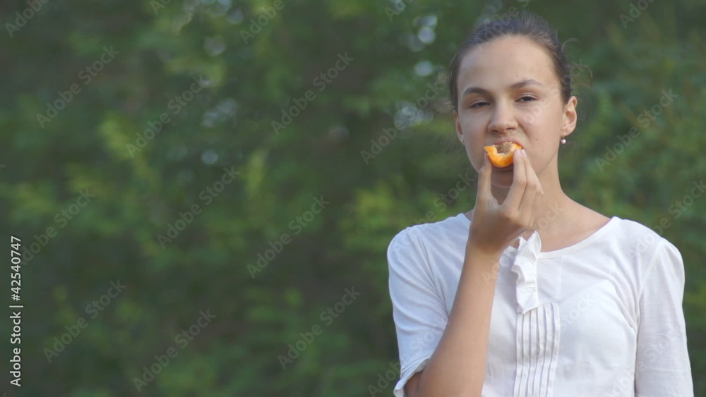 Teenage girl eating apricot outdoors in park Teenage girl eating apricot outdoors in park