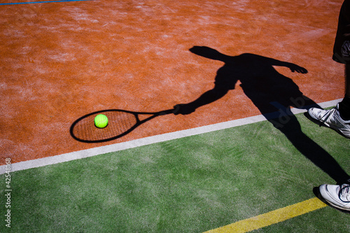 shadow of a tennis player in action on a tennis court  photo
