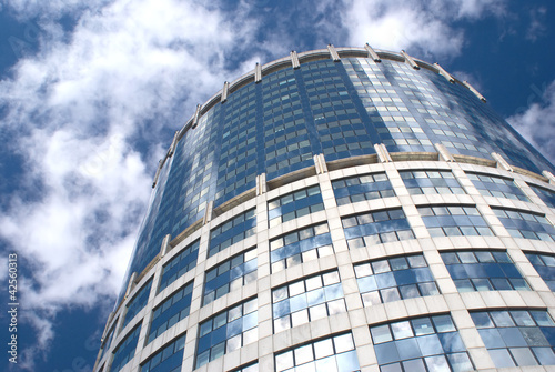 Modern office round tower building over sky with clouds