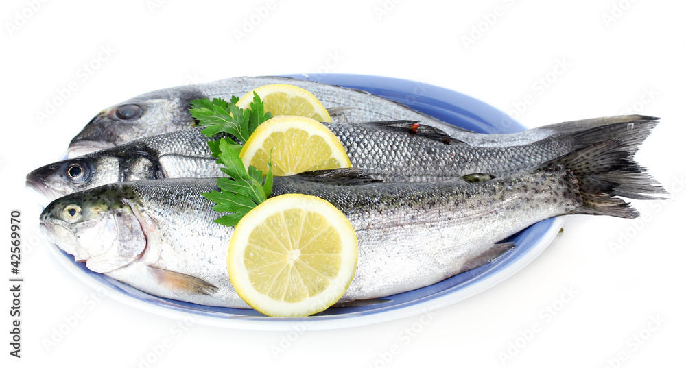 Fresh fishes with lemon and parsley on plate isolated on white Fresh fishes with lemon and parsley on plate isolated on white