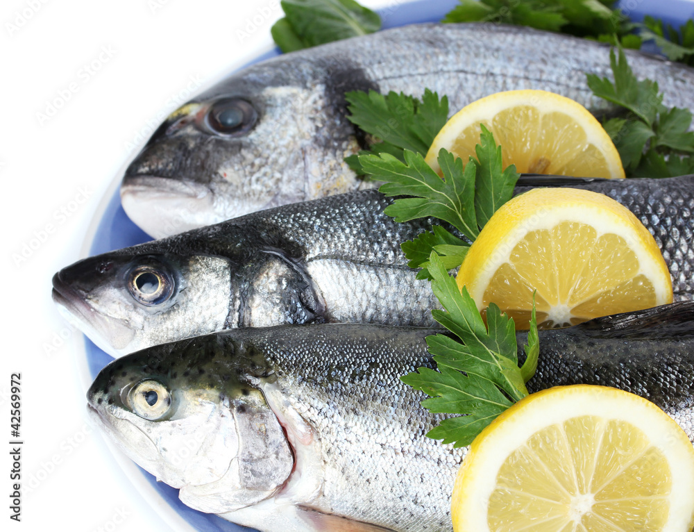 Fresh fishes with lemon and parsley on plate isolated on white