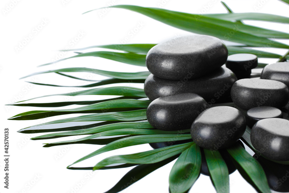 Spa stones on green palm leaf on grey background Spa stones on green palm leaf on grey background