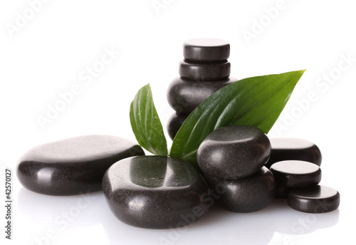 Spa stones and green leaves isolated on white