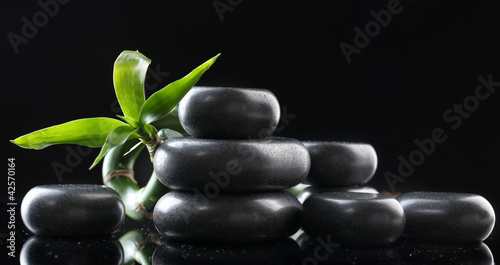 Spa stones and green bamboo on grey background