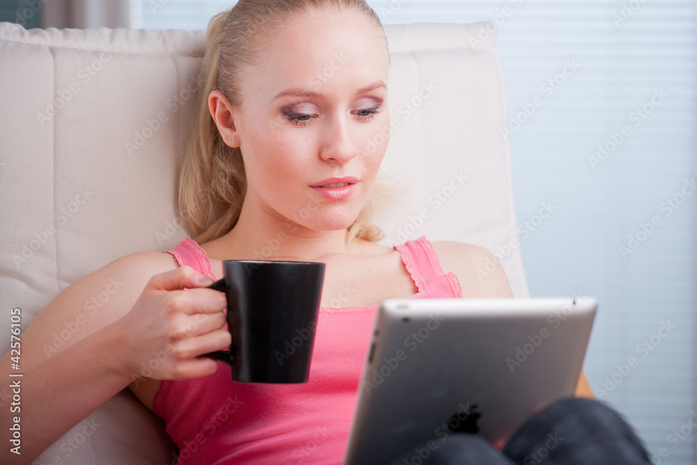 Young beautiful student using a tablet computer while relaxing
