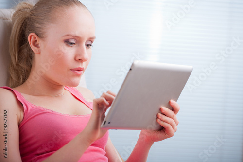 Young beautiful student using a tablet computer while relaxing
