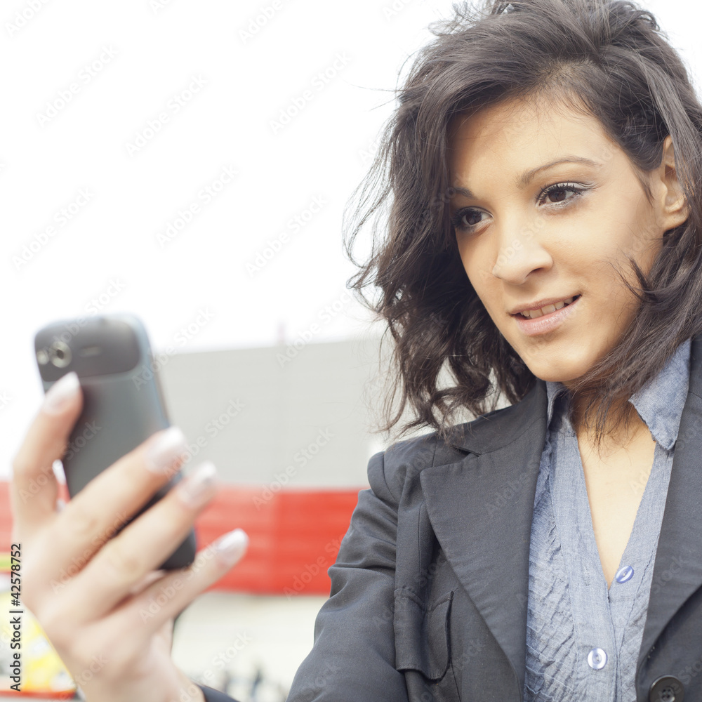 Young Woman with cell phone walking, blured business building in