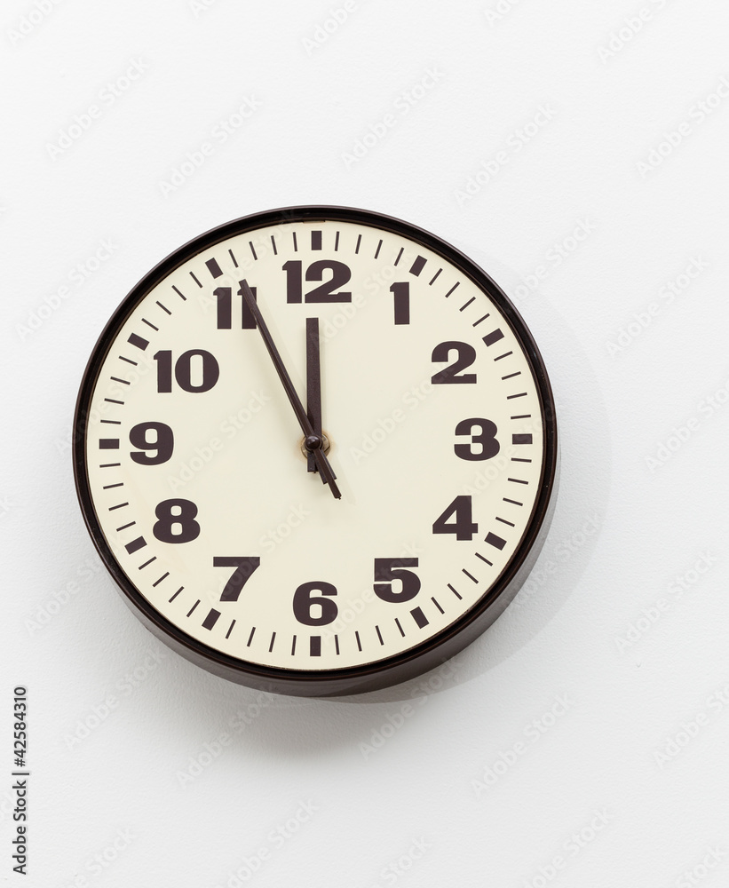 Brown clock on white office wall near noon Brown clock on white office wall near noon