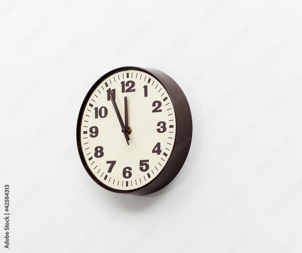 Brown clock on white office wall near noon Brown clock on white office wall near noon