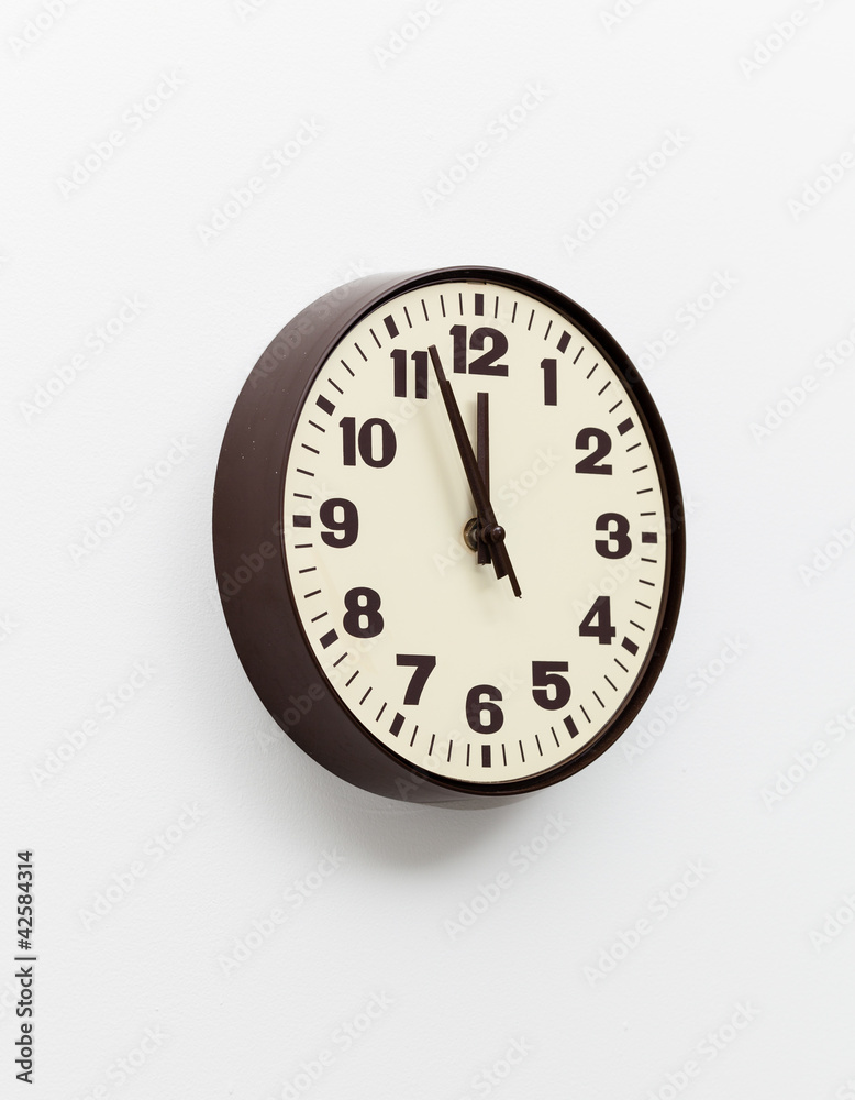 Brown clock on white office wall near noon Brown clock on white office wall near noon