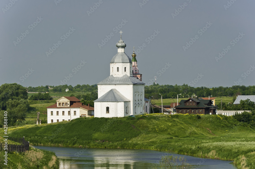 Белая русская церковь на берегу реки.