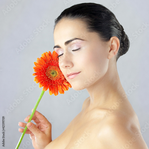 Młoda pani z zamyśloną miną i piękna gerbera