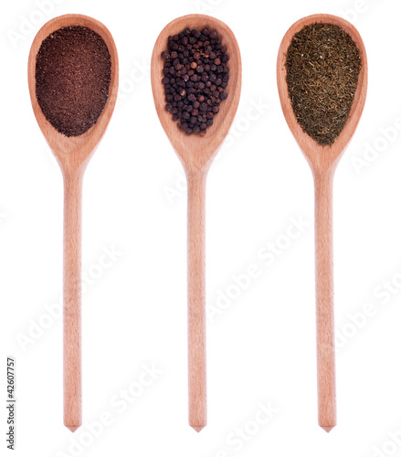 Pepper, black pepper, dried dill in three wooden spoons