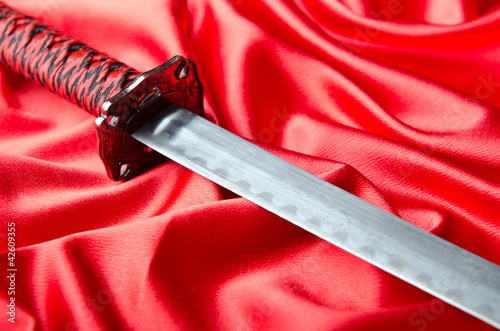 Japanese sword takana on red satin background photo