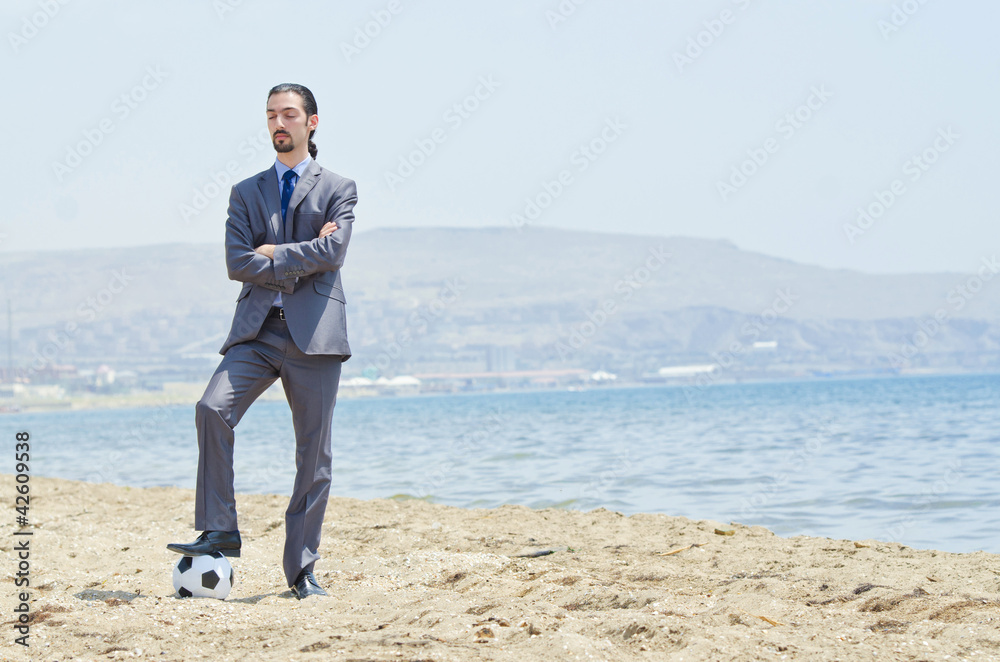 Businessman with football on beach Businessman with football on beach