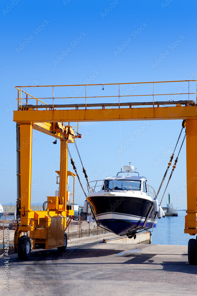 crane travelift lifting a boat on blue sky day crane travelift lifting a boat on blue sky day
