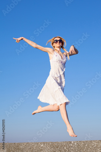 Attractive young woman in white sundress running