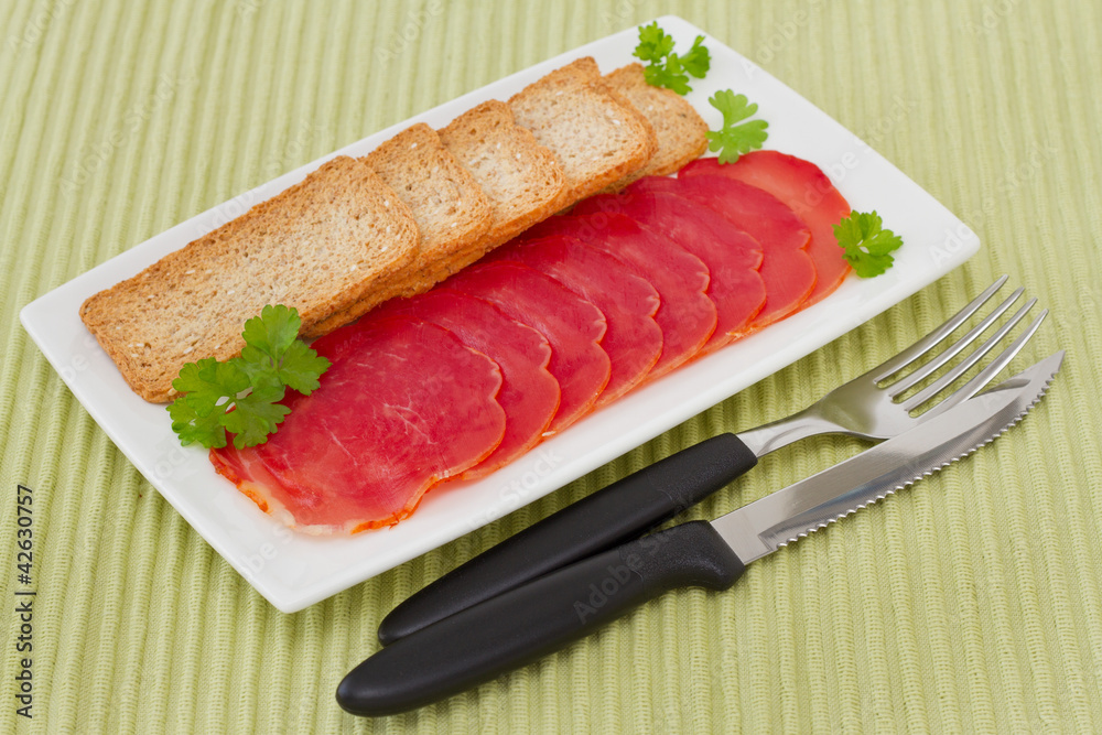 prosciutto with toasts on the white plate prosciutto with toasts on the white plate