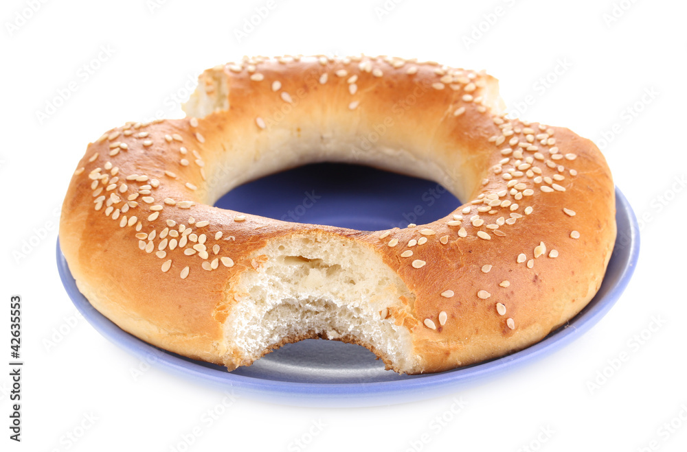Bitten bagel with sesame seeds on plate isolated on white