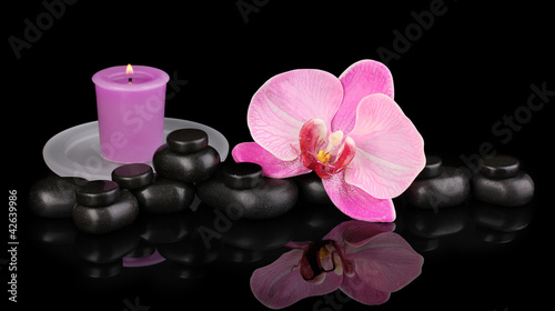 Spa stones with orchid flower and candle isolated on black